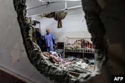 People inspect the damage in a room following Israeli bombardment at Nasser hospital in Khan Yunis in the southern Gaza Strip on Dec. 17, 2023.