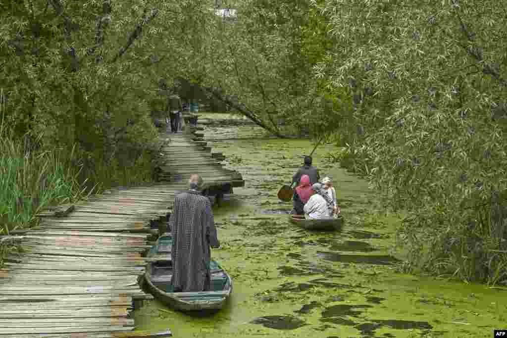 A boatman (R) steers a boat with residents along a canal in the interior of Dal Lake after water levels rose due to heavy rains, in Srinagar, Indian-administered Kashmir.