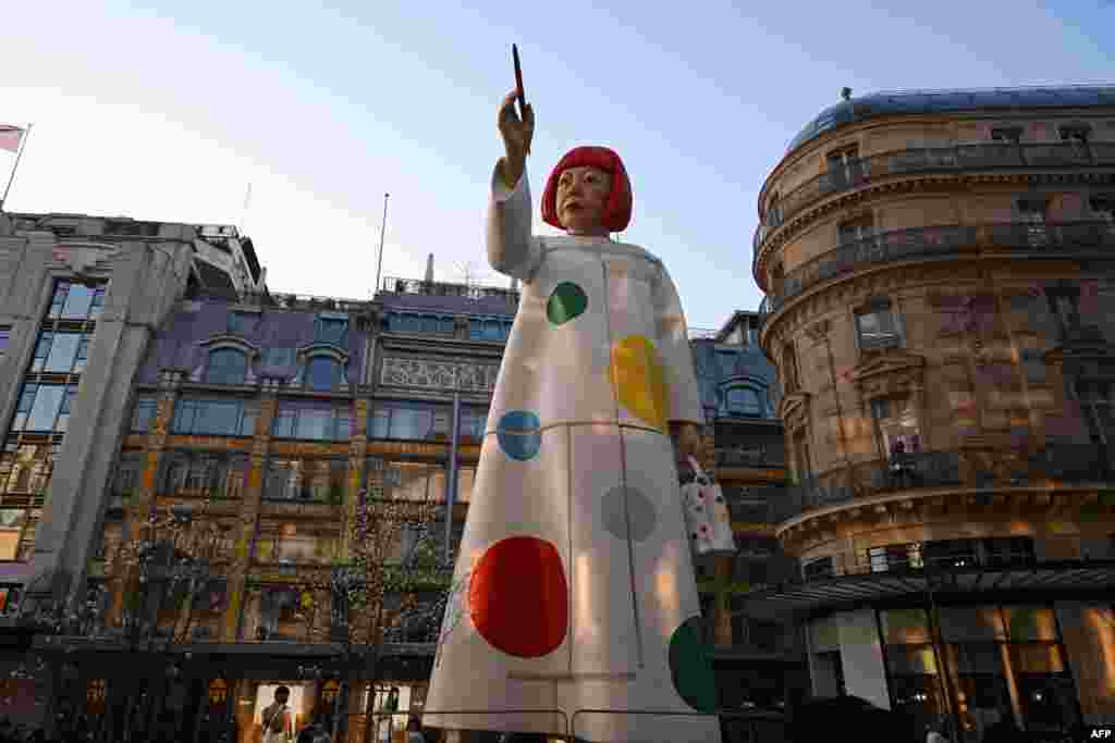 A large statue depicting Japanese contemporary artist Yayoi Kusama is seen pointing a paintbrush towards the French luxury brand Louis Vuitton headquarters in Paris, France.