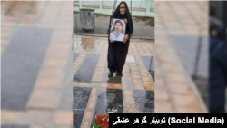گوهر عشقی، مادر دادخواه ستار بهشتی، بر مزار فرزندش در حالی که عکس محمد حسینی معترض اعدام‌شده را در دست دارد
