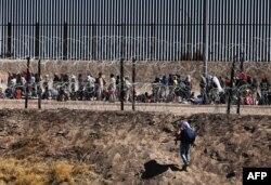 Seorang pria migran melintasi tepian Rio Grande untuk diproses oleh Patroli Perbatasan Sektor El Paso, Texas, setelah menyeberang dari Ciudad Juarez, Meksiko, 10 Mei 2023. (HERIKA MARTINEZ / AFP)