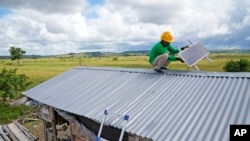 Antonius Makambombu, seorang pekerja dari organisasi Sumba Sustainable Solutions tampak memperbaikin panel surya di atap rumah warga di desa Laindeha, Sumba, pada 22 Maret 2023. (Foto: AP/Dita Alangkara)