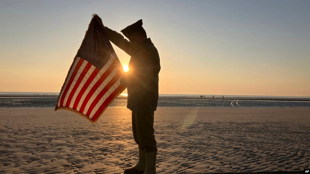 Christophe Receveur, de Francia, despliega una bandera estadounidense que compró hace seis meses en Gettysburg, Pensilvania, para conmemorar el Día D, el jueves 6 de junio de 2024 en Utah Beach, Normandía.