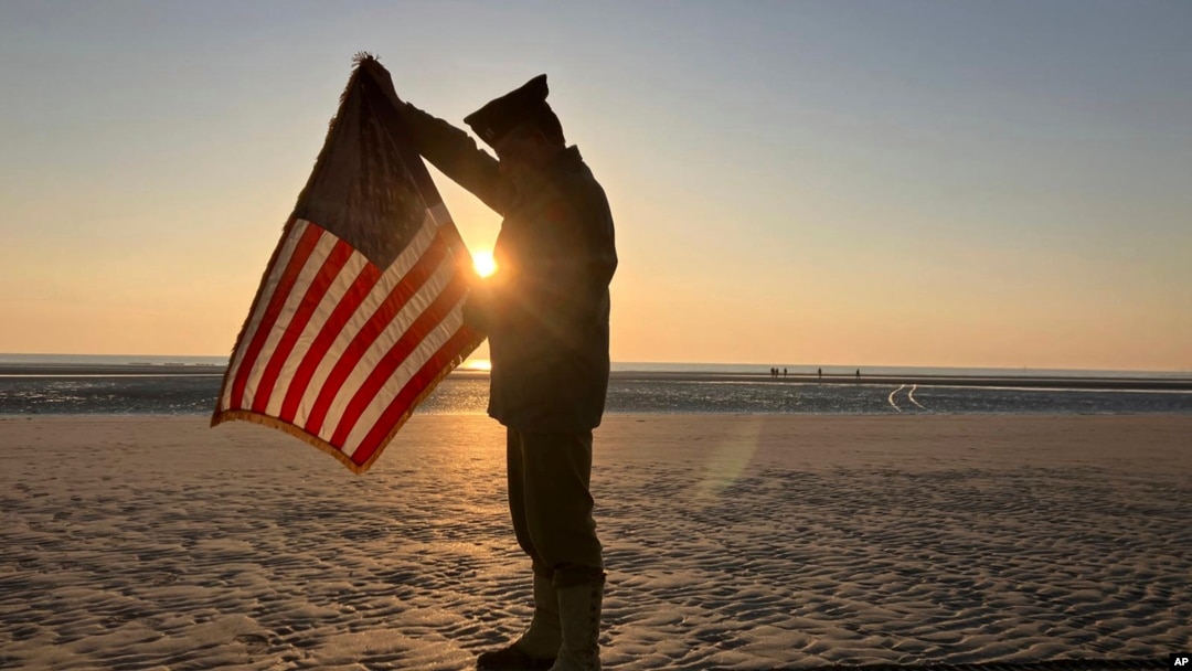 Christophe Receveur, de Francia, despliega una bandera estadounidense que compró hace seis meses en Gettysburg, Pensilvania, para conmemorar el Día D, el jueves 6 de junio de 2024 en Utah Beach, Normandía.
