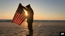 Christophe Receveur, de Francia, despliega una bandera estadounidense que compró hace seis meses en Gettysburg, Pensilvania, para conmemorar el Día D, el jueves 6 de junio de 2024 en Utah Beach, Normandía.