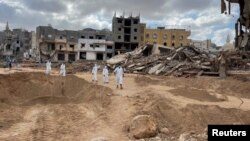 Sejumlah relawan bergerak untuk mencari korban tewas di area yang telah hancur akibat banjir di Libya di Derna, pada 18 September 2023. (Foto: Reuters/Ahmed Elumami)