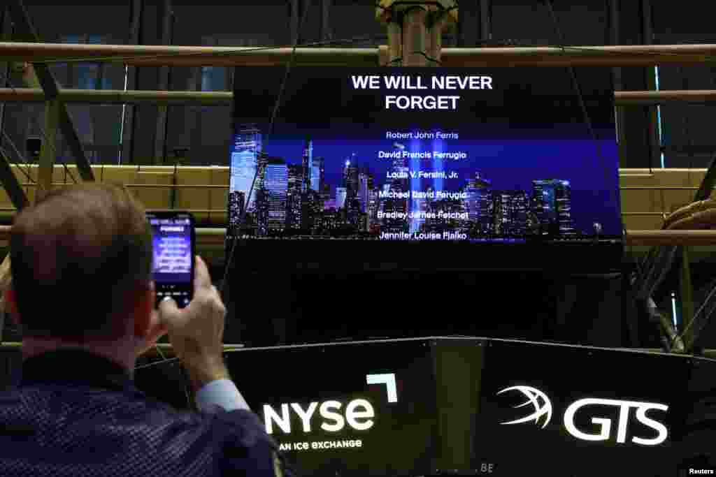 A trader photographs a list of names displayed on a screen of victims of the September 11, 2001 attacks on the 22nd anniversary, on the floor at the New York Stock Exchange, in New York City.