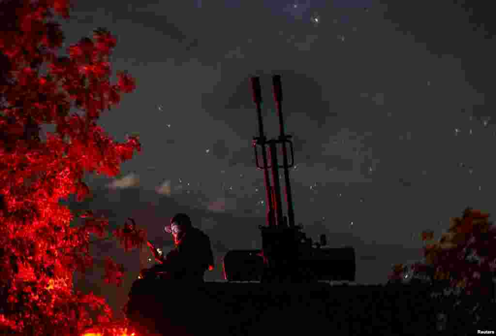 A Ukrainian serviceman from an anti-drone mobile air defence unit uses his mobile device near a ZU-23-2 anti aircraft cannon in Kherson region, June 11, 2024. 