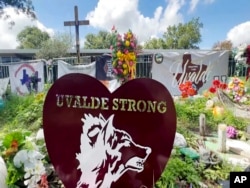 FILE - Posters, flowers and portraits fill the lawn in front of Robb Elementary School in Uvalde, Texas, on Sept. 6, 2022.