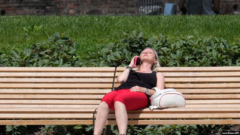 ARCHIVO - Una mujer toma el sol en un parque de Milán, Italia, el 16 de julio de 2024.