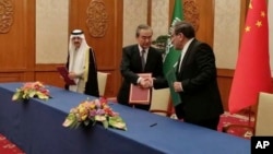Iranian security council official Ali Shamkhani shakes hands with China's senior foreign policy official Wang Yi as Saudi security adviser Musaad bin Mohammed al-Aiban watches during a signing of an accord to reset Iranian-Saudi ties, in Beijing, March 10, 2023. (Nournews via AP)