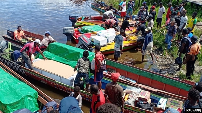 Para pekerja mengantarkan kotak suara dengan perahu ke desa-desa terpencil di Mappi, Provinsi Papua pada 2019. (Foto: Courtesy/Komisi Pemilihan Umum/AFP)