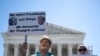 Sejumlah warga memegang poster yang memprotes keputusan Mahkamah Agung AS yang memberikan imunitas kepada Trump, dalam aksi protes di depan gedung MA di Washington, pada 1 Juli 2024. (Foto: AFP/Drew Angerer)