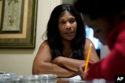 Evena Joseph, left, sits with her son J. Ryan Mathurin, 9, as he does his homework, Thursday, Dec. 22, 2022, at their home, in Boston. (AP Photo/Steven Senne)