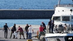 A child escorted by coast guard officers disembarks with other migrants from a vessel after a rescue operation, at the port of Mytilene, on the northeastern Aegean Sea island of Lesbos, Greece, Aug. 28, 2023.