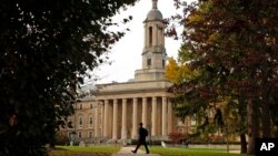 FILE- In this Nov. 9, 2017, photo, people walk by Old Main on the Penn State University main campus in State College, Pa. 