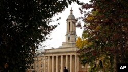 FILE- In this Nov. 9, 2017, photo, people walk by Old Main on the Penn State University main campus in State College, Pa. 