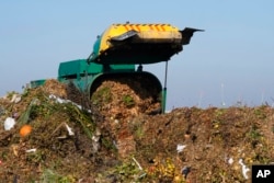 FILE - A truck unloads organic waste to be used for composting at the Anaerobic Composter Facility in Woodland, California, Nov. 30, 2021.