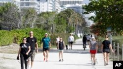 ILUSTRASI - Orang-orang berjalan-jalan dengan anjing mereka dan berolahraga di jalan yang padat di sepanjang sisi pantai, Sabtu, 21 Maret 2020, di Surfside, Florida. (AP/Wilfredo Lee)