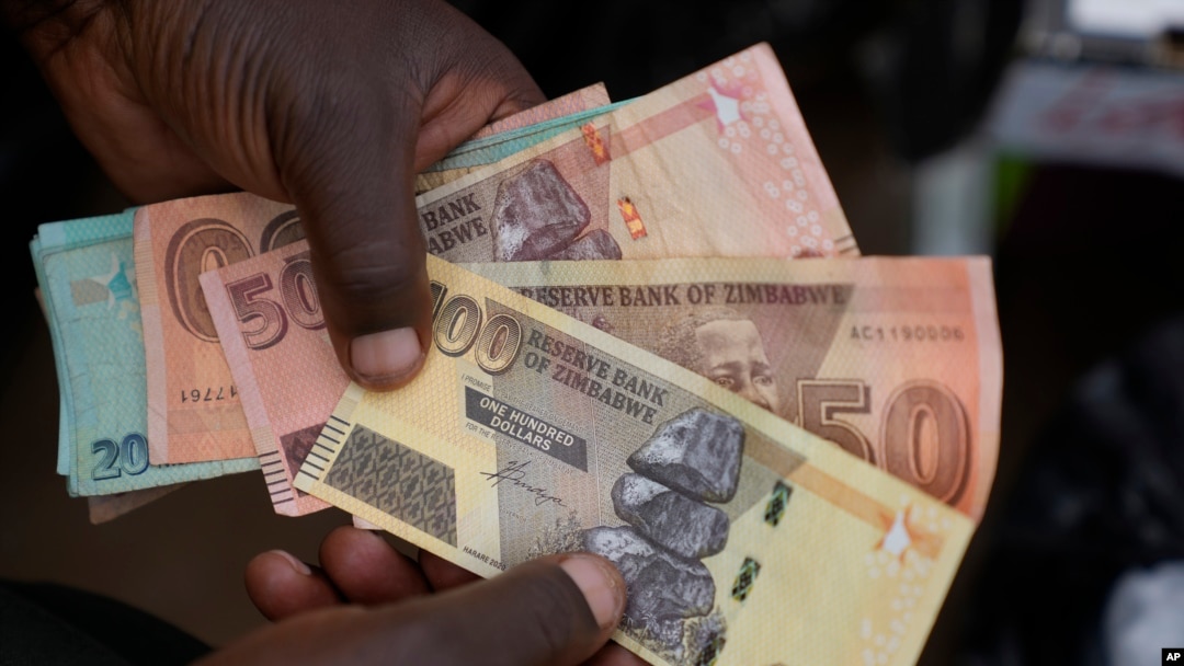 FILE - A currency trader holds worthless Zimbabwean dollar notes on the streets of Harare, Zimbabwe, June, 9, 2022.