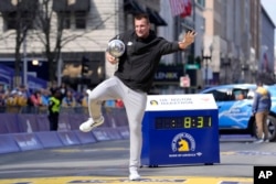 Former New England Patriots NFL football player Rob Gronkowski holds the Boston Marathon trophy at the finish line of the Boston Marathon in Boston, April 15, 2024.