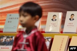 Seorang anak berdiri di depan rak buku yang memajang buku tentang Presiden China Xi Jinping dalam Pameran Buku Hong Kong ke-33, di Hong Kong, 19 Juli 2023. (Foto: May James/AFP)