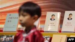 FILE - A boy wearing Chinese traditional clothes stands in front of a booth displaying Chinese President Xi Jinping's books at the 33rd Hong Kong Book Fair in the Wan Chai area of Hong Kong on July 19, 2023.