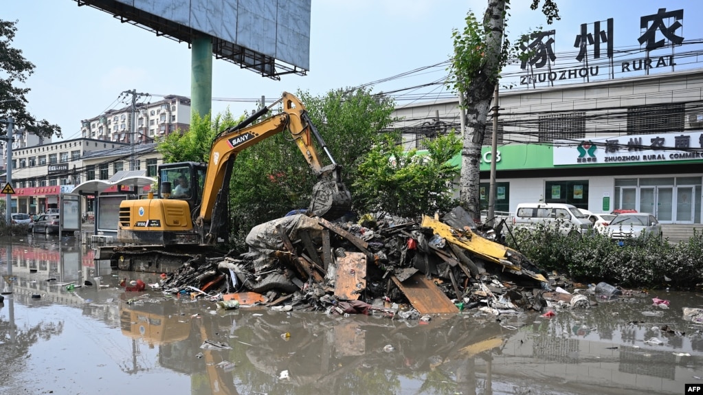 中国河北省涿州工人在清理遭洪水淹没的街道。（2023年8月9日）