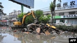 中国河北省涿州工人在清理遭洪水淹没的街道。（2023年8月9日）