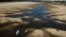 FILE - Birds fly over a man taking photos of the exposed riverbed of the Old Parana River, a tributary of the Parana River during a drought in Rosario, Argentina, July 29, 2021.