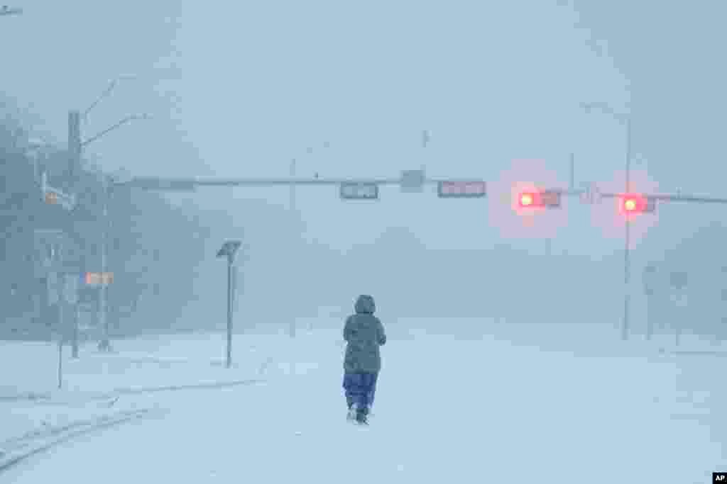 A jogger trots on a snow-covered road during a winter storm in Grand Prairie, Texas.