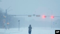 A jogger trots on a snow-covered road during a winter storm in Grand Prairie, Texas.