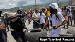 (FILE) A police officer holding a gun confronts a demonstrator during a protest in Haiti.