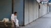 A man sits beside closed shops during a strike against recent price increases, in Karachi, Pakistan, Feb. 27, 2023.