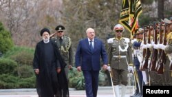 Presiden Iran Ebrahim Raisi berjalan dengan Presiden Belarus Alexander Lukashenko dalam upacara penyambutan di Teheran, Iran, pada 13 Maret 2023. (BelTA/handout via Reuters)