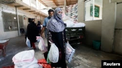 People receive charity ration sacks from the Saylani Welfare Trust's office, a non-government organization focusing primarily on feeding the poor and homeless, in Karachi, Pakistan, April 3, 2023.