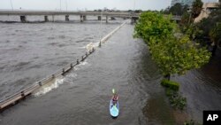 Floodwater pushed by Hurricane Idalia pours over the seawall along Old Tampa Bay as Zeke Pierce of Tampa rides a paddle board, Aug. 30, 2023, in Tampa, Florida. Idalia made landfall earlier Wednesday morning along the Big Bend of the state.