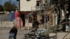 FILE - A man walks with his bicycle through a shopping street destroyed by Russian strikes in the town of Kupiansk, Ukraine, Oct. 18, 2022. 