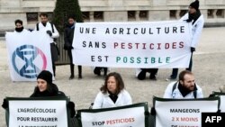 FILE: Activists hold a banner that says "A pesticide-free agriculture is possible" during a demonstration in Paris to reduce pesticides by 60 percent by 2023 and 90 percent by 2050. Taken March 4, 2023.