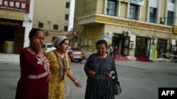 FILE - This picture taken July 19 , 2023, shows women walking in Artux, northwestern China's Xinjiang region.