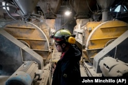 A worker stands beside the mixing machines at the start of a production line creating concrete blocks designed with liquid carbon dioxide as an ingredient at the Glenwood Mason Supply Company, Tuesday, April 18, 2023, in the Brooklyn borough of New York. (AP Photo/John Minchillo)