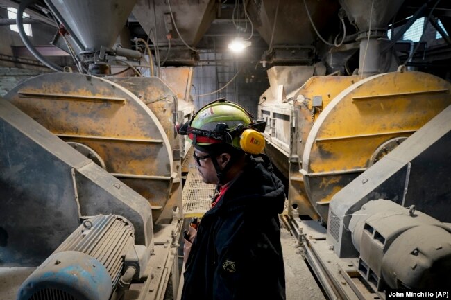 A worker stands beside the mixing machines at the start of a production line creating concrete blocks designed with liquid carbon dioxide as an ingredient at the Glenwood Mason Supply Company, Tuesday, April 18, 2023, in the Brooklyn borough of New York. (AP Photo/John Minchillo)