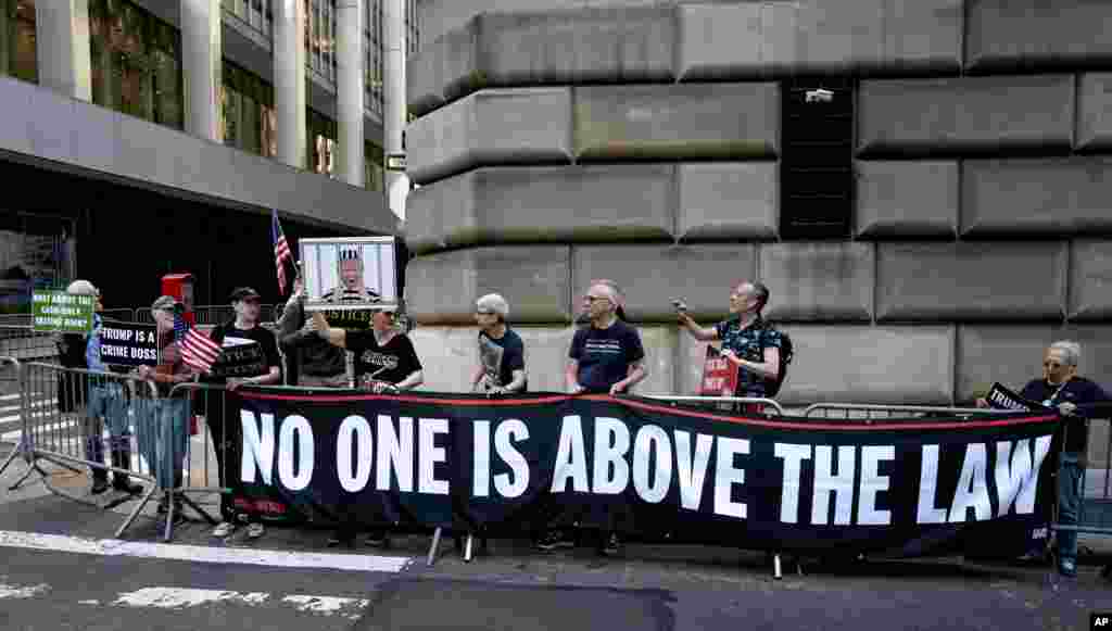Para pengunjuk rasa berkumpul menjelang kedatangan iring-iringan mobil untuk deposisi mantan Presiden Donald Trump di New York.