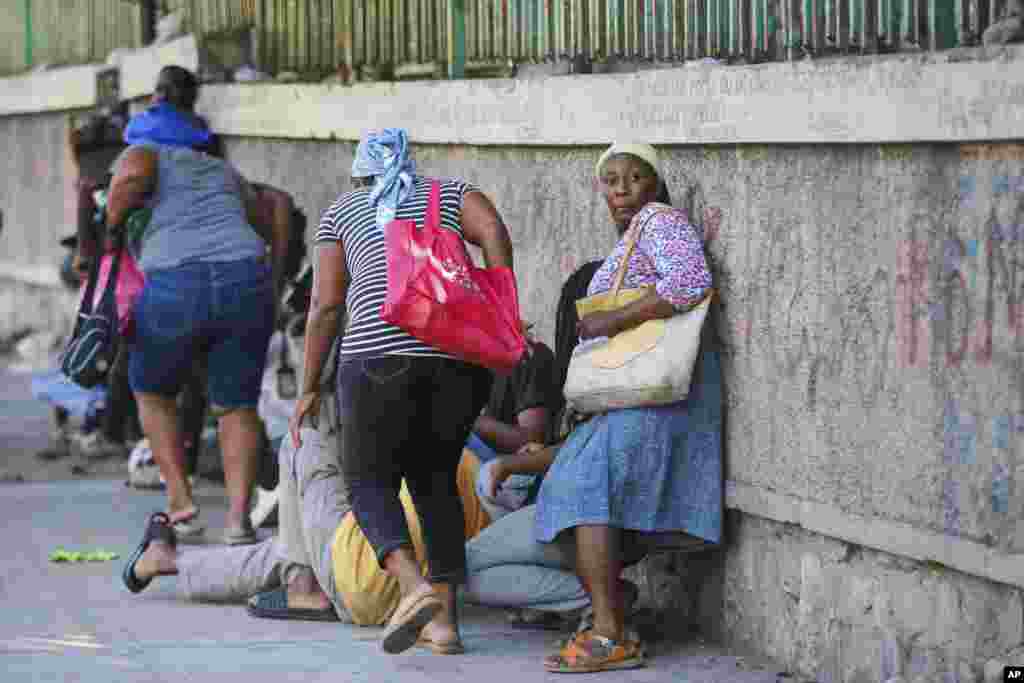 Los transeúntes se refugian y permanecen agrupados durante los enfrentamientos entre la policía y pandilleros en la capital de Haití, el viernes 1 de marzo de 2024. Las pandillas han aumentado el control de algunas partes de Puerto Príncipe desde que en julio de 2021 un comando internacional asesinó al entonces presidente Jovenel Moise.