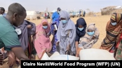 FILE - People receive bags of relief grains at a camp for the Internally Displaced People in Adadle district in the Somali region, Ethiopia on January 22, 2022.