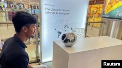 FILE - An engineer in Bengaluru, India, signs up for Worldcoin by having his eyes scanned by the spherical device at a local mall on July 25, 2023. A panel in Kenya has urged the shutdown of the crypto project there pending more stringent regulations. 