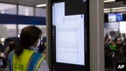 A technician works on an information display near United Airlines gates at Chicago O'Hare International Airport in Chicago, Friday, July 19, 2024. (AP Photo/Carolyn Kaster)