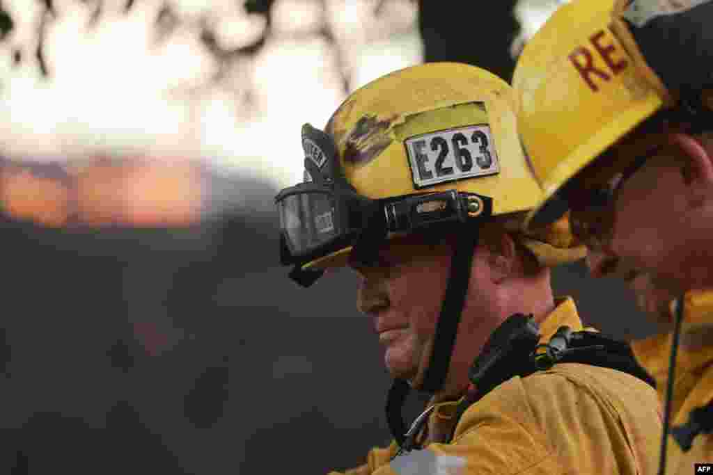 Los bomberos trabajan en el lugar del incendio que destruyó varias casas y vehículos. Durante el día, las temperaturas alcanzaron los 41,6 grados Celsius.