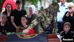 A fighter of the Russian private military company Wagner Group lays flowers on the coffin of a comrade killed during Russia-Ukraine conflict, at a cemetery in Volgograd, Russia, May 21, 2023.