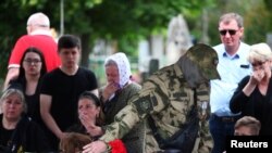 Seorang anggota pasukan Wagner meletakkan bunga pada peti jenazah dari rekannya yang tewas dalam konflik Rusia-Ukraina, di taman pemakaman di Volgograd, Rusia, pada 21 Mei 2023. (Foto: Reuters/Stringer)